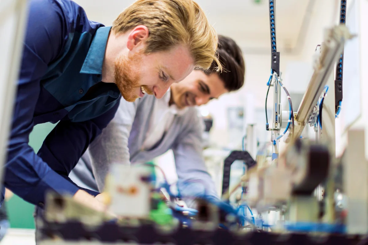Two young handsome engineers working on electronics components and fixing broken chips