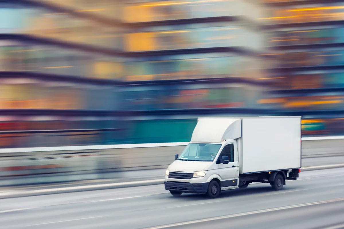 A delivery truck travelling fast on a city street with motion blurred office buildings in the background.